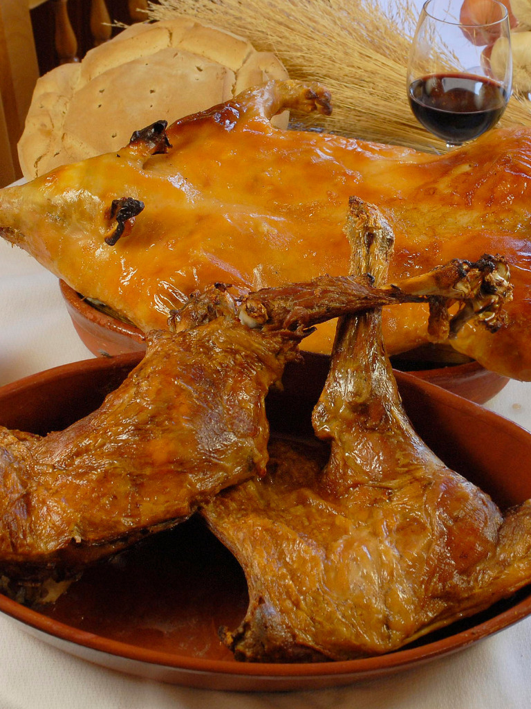 WhatsApp Image 2026-04-29 at 11.30.37 Raciones de cochinillo asado tradicional, paletillas y piezas recién cortadas en un restaurante de la franquicia Asador de Segovia.