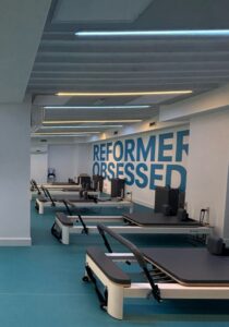 Amplia y luminosa sala de máquinas Reformer y Springboard en una de las franquicias de pilates Qombo