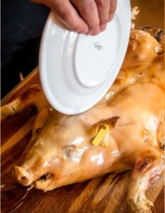 Corte tradicional de cochinillo asado al estilo segoviano en un restaurante de la franquicia Asador de Segovia. Un cocinero parte la pieza crujiente.